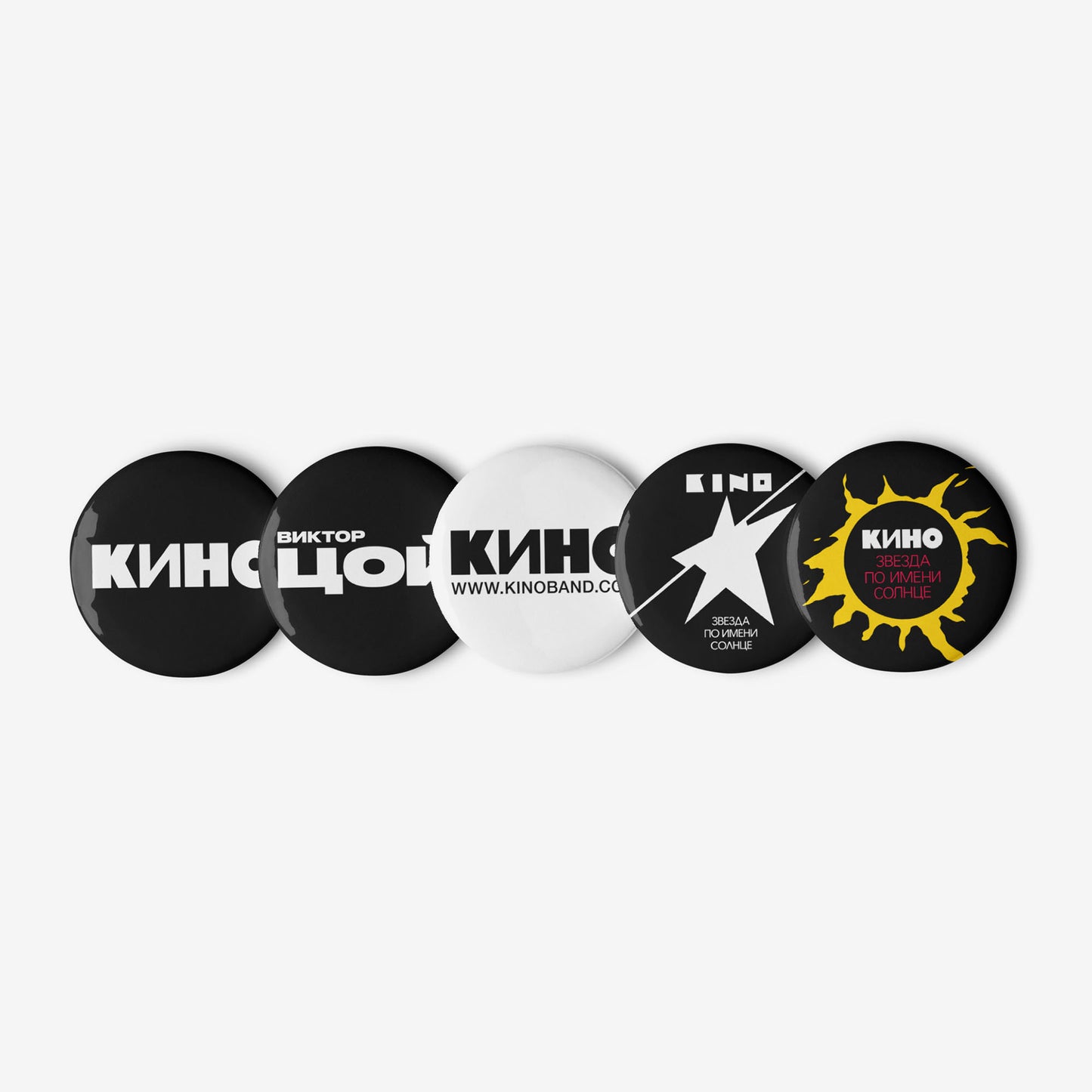 Set of five 3cm official KINO (КИНО) band pin buttons: two classic logo pins, one Viktor Tsoi Cyrillic logo pin, and two pins featuring different Zvezda po Imeni Solntse album art designs. Laid in a line. www.kinoband.com