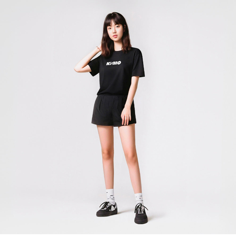 Cute young asian looking model girl wearing black unisex T-shirt with official KINO band logo (Группа Кино). Authentic Viktor Tsoi Soviet rock merch from www.kinoband.com