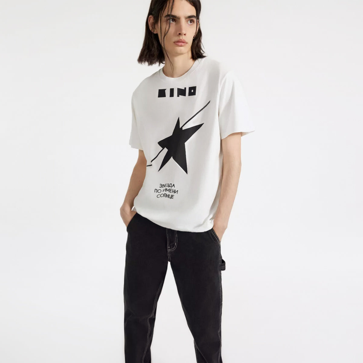 A young handsome boy model wearing premium unisex white T-shirt with official 'A star called Sun' (Zvezda) album cover by Viktor Tsoi and Gruppa Kino band. From kinoband.com