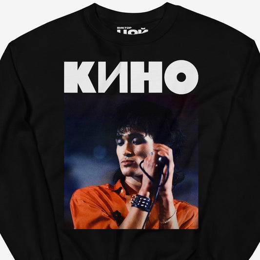 Black unisex sweatshirt with large Viktor Tsoi concert photo and KINO band logo above. Closeup photo with custom necktag design seen with Viktor Tsoi logo in Cyrillic. Closeup photo. From www.kinoband.com