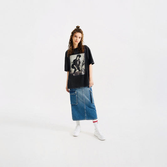 Beautiful young model girl in a photo studio wearing official KINO band tshirt (black unisex Tee) with large rare photo of Viktor Tsoi in wearing a bomber jacket with guitar in an apartment. Closeup photo. From kinoband.com