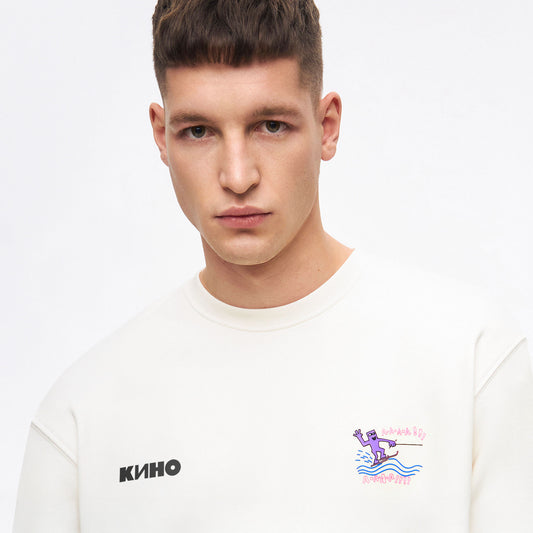 A model boy wearing white unisex KINO band sweatshirt featuring an original painting by Viktor Tsoi with a small КИНО logo on the chest, with custom necktag logo design in Cyrillic "Виктор Цой”. www.kinoband.com
