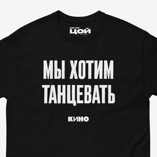 Black T-shirt with white Cyrillic KINO band song lyric 'We wanna dance' and KINO logo underneath. Closeup photo. Viktor Tsoi merch from www.kinoband.com