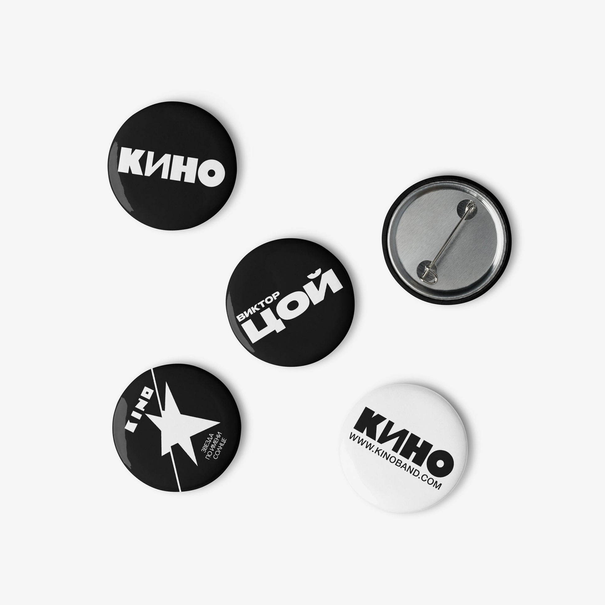 Set of five 3cm official KINO (КИНО) band pin buttons: two classic logo pins, one Viktor Tsoi Cyrillic logo pin, and two pins featuring different Zvezda po Imeni Solntse album art designs. Laid randomly on white. www.kinoband.com