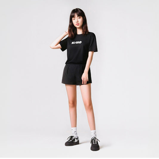 Cute young asian looking model girl wearing black unisex T-shirt with official KINO band logo (Группа Кино). Authentic Viktor Tsoi Soviet rock merch from www.kinoband.com