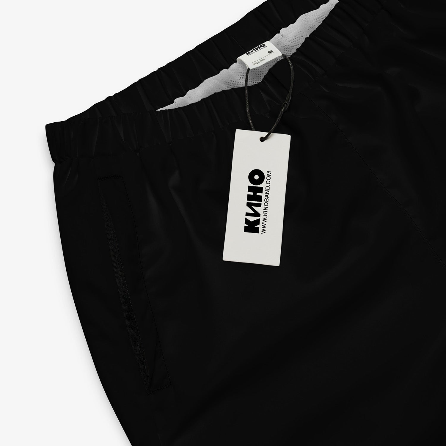 Black official KINO band sport pants like Viktor Tsoi had. With KINO logo on the left pant. Premium cuffed joggers. Closeup photo with logo on the tag. From www.kinoband.com