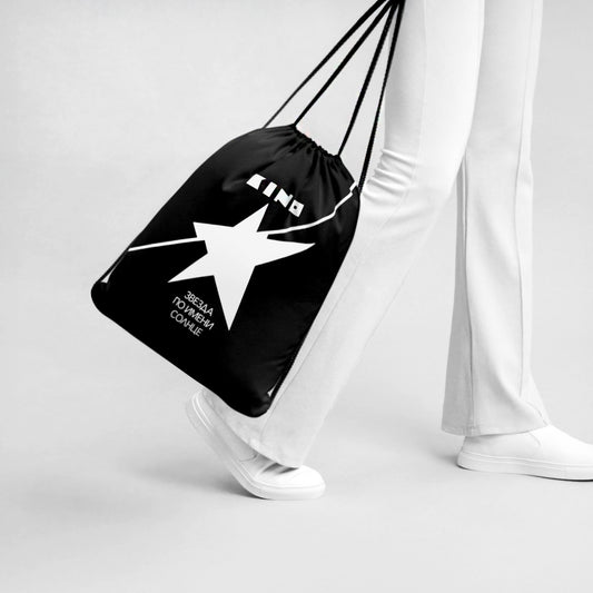 A model holding official KINO band black drawstring bag with Star Called Sun album artwork – white star and name of the album. Professional studio photo. www.kinoband.com