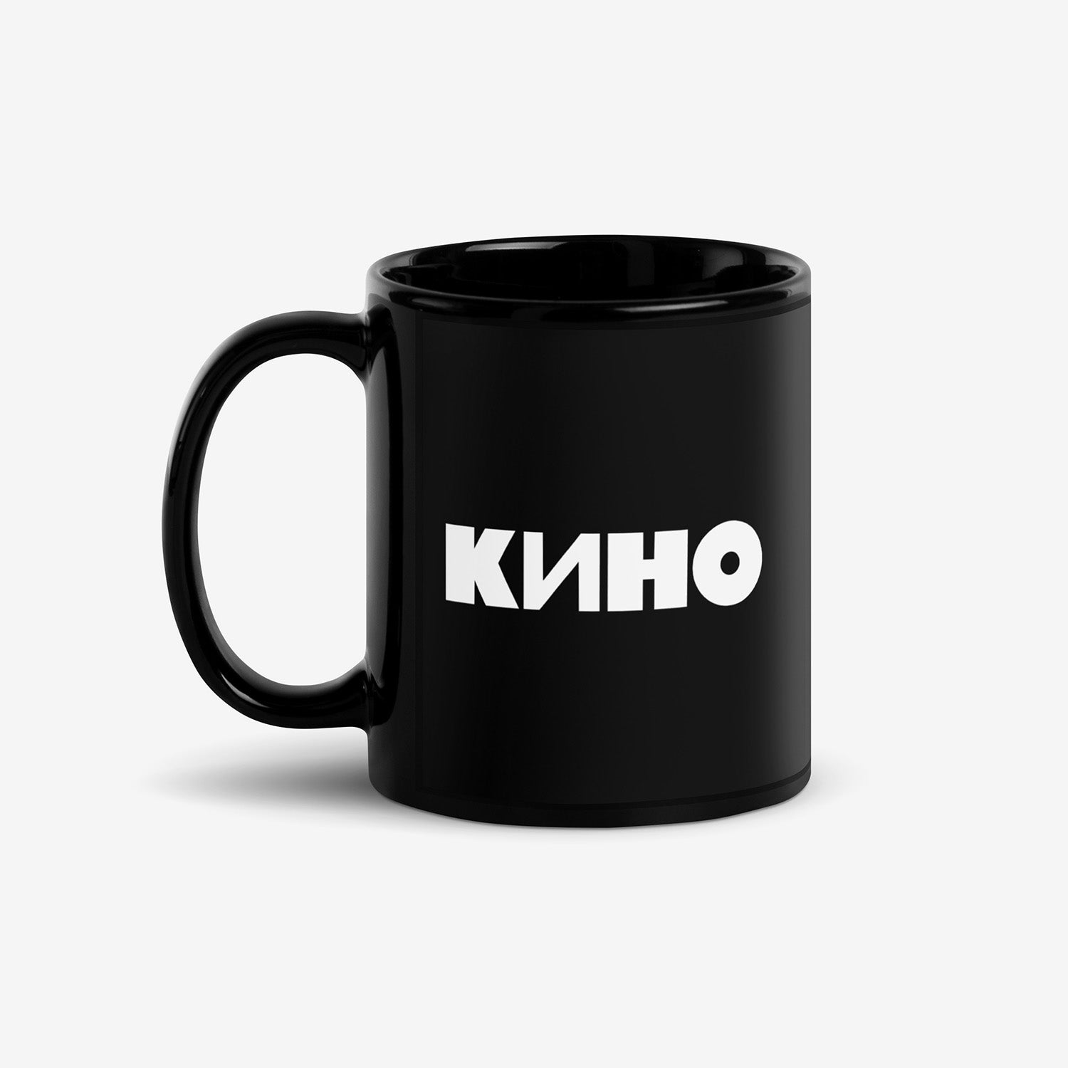 Black coffee mug with bold white КИНО (KINO band) logo on the front and Viktor Tsoi (Виктор Цой) in Cyrillic on the back. Official Viktor Tsoi Soviet rock merch. Front side. From www.kinoband.com