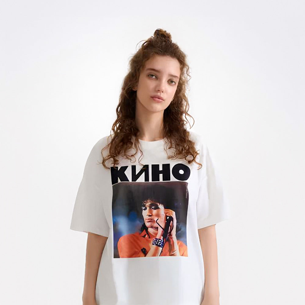 Cute young model girl wearing white t-shirt with large photo of Viktor Tsoi performing live and bold KINO band logo above. From kinoband.com