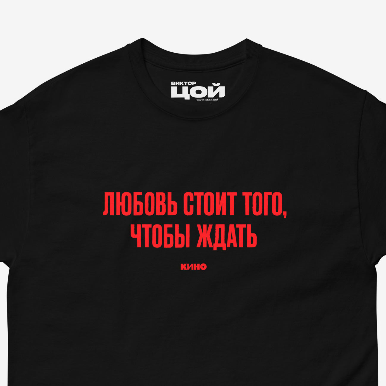 Black T-shirt with KINO band lyrics “Любовь стоит того, чтобы ждать”. Closeup photo with visible necktag design. Original Viktor Tsoi merch from www.kinoband.com